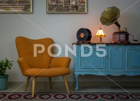 Vintage interior of retro orange armchair, vintage wooden light blue sideboar Stock Photos