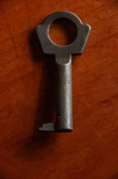 A vintage iron skeleton key on a rustic wooden surface Stock Photos