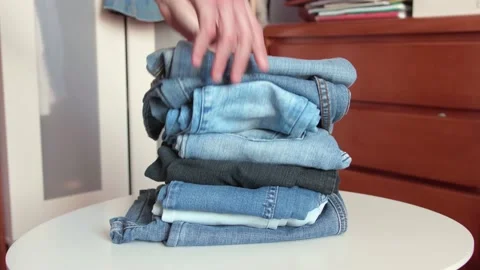Vintage jeans being piled up on a table Stock Footage 154297679