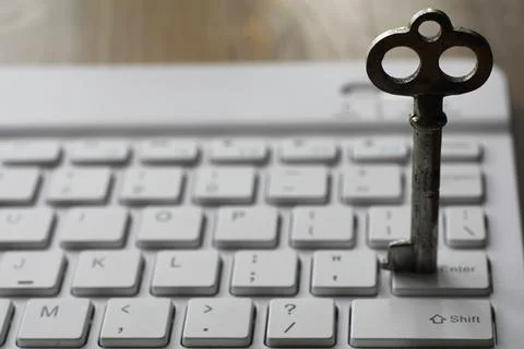 Vintage Key on Computer Keyboard: Symbolizing Digital Security and Access Stock Photos