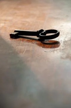 A vintage key on a table with a long shadow Stock Photos