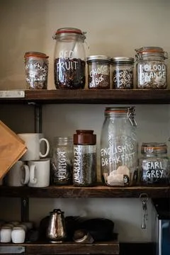 Vintage Kitchen Shelf Displaying Assorted Loose Leaf Teas and Mugs. Stock Photos