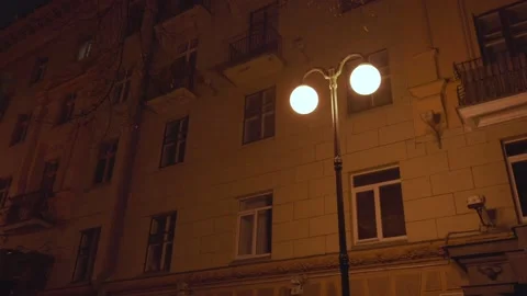 Vintage lamppost with dim light stands at night city street against luxury hotel 스톡 동영상 167084126