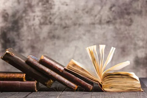 Vintage leather books stack on old rustic wooden surface Stock Photos