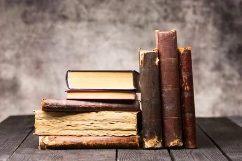 Vintage leather books stack on old rustic wooden surface Stock Photos
