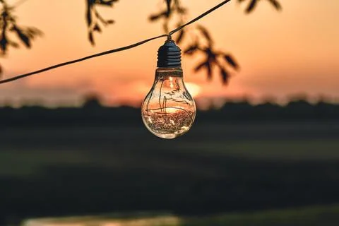 Vintage light bulbs on string wire against sunset decor in outdoors wedding p Stock Photos