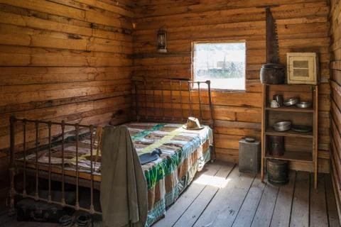 Vintage lumberjack cabin interior - bed, shelf, and kitchen utensils Stock Photos