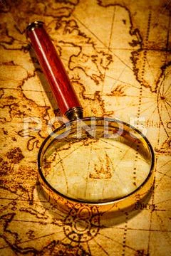Vintage magnifying glass lies on an ancient world map Stock Photos