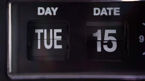 Vintage mechanical flip clock showing date card mid-flip, Tuesday 15 display Stock Footage 346221984