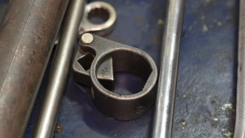 Vintage metal tool with circular ring and triangular cutout on blue workbench Vídeo Stock 347640486