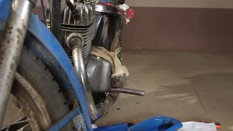 Vintage motorcycle engine with its blue fender, exhaust, and wheel visible Stock Footage 340430357