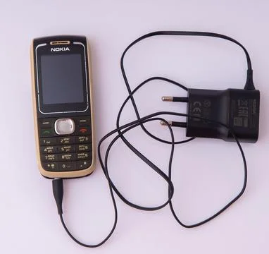 Vintage Nokia push button mobile phone with wall charger. Classic cellular te Stock Photos