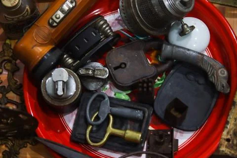 Vintage orange flashlight rusty padlocks and lighters arranged in red tray Stock Photos