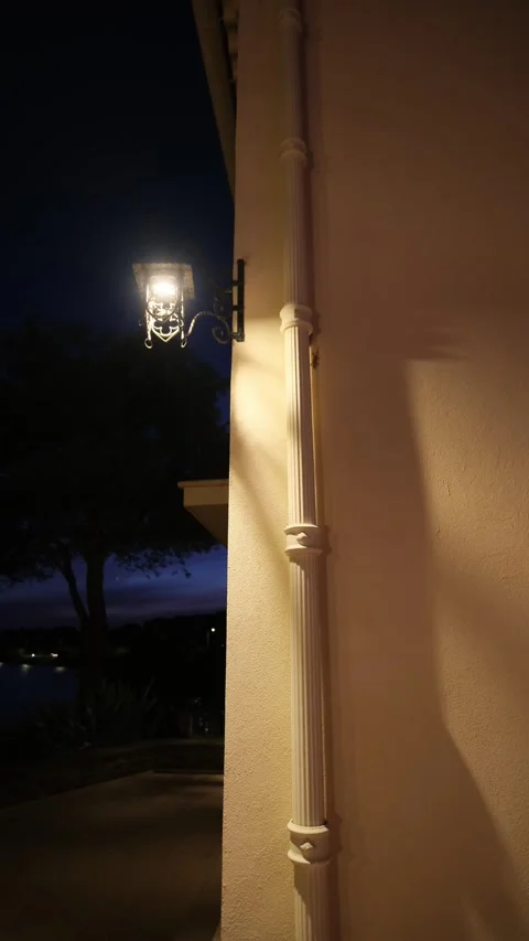 Vintage outdoor lantern casting warm glow and long shadows on a building facade 库存影片 344007438