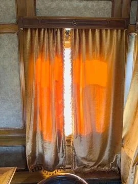 Vintage passenger train interior featuring luxurious curtains, warm golden .. Stock Photos