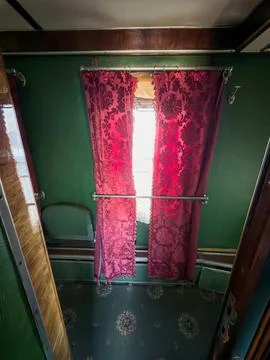 Vintage passenger train interior featuring luxurious red floral curtains, e.. Stock Photos