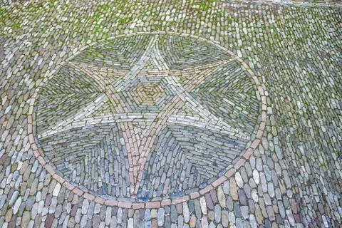 Vintage paving stone of pattern of star with moss from medieval time Stock Photos