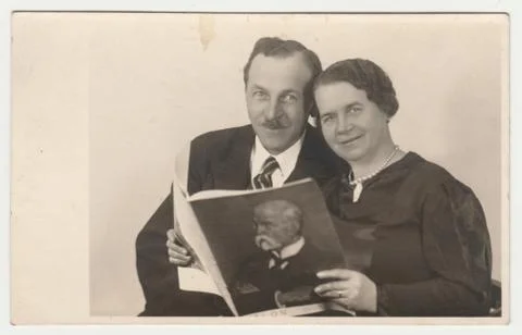 Vintage photo shows a marital  couple pose with magazine. The cover page of m Stock Photos