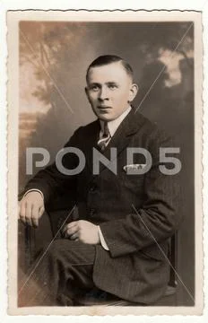 Vintage photo shows young man poses in a photography studio. Antique black & Stock Photos