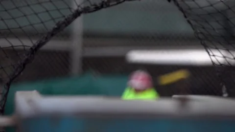 A vintage pitching machine throws a yellow baseball towards a batter during batt Stock Footage 70466357