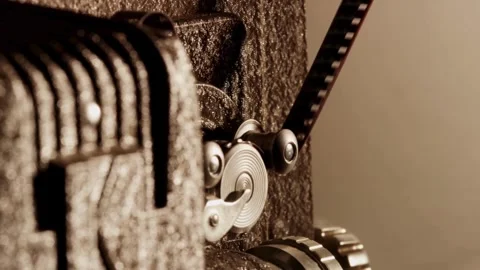 Vintage projector gears rotate while moving the film strip Stock Footage 329745869