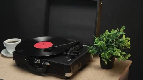 Vintage record player with coffee and plant on wooden table Vidéo 340844672
