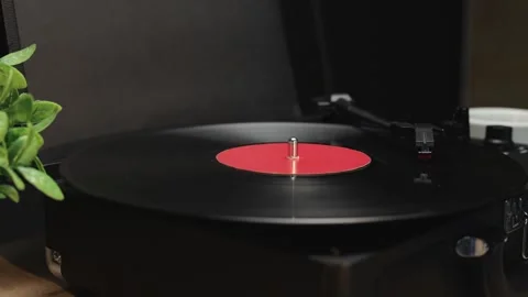 Vintage record player spinning a black vinyl disc with a red label Stockbeeldmateriaal 340844859