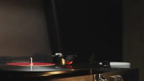 Vintage record player spinning a red vinyl disc with warm lighting Vidéo 340844901