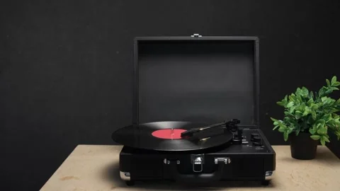 Vintage record player with vinyl disc spinning and plant in background Vidéo 340844694