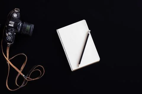 Vintage retro camera and notepad on black background, flat lay. Stock Photos