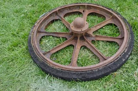 Vintage solid rubber wagon wheel laid down on grass Stock Photos