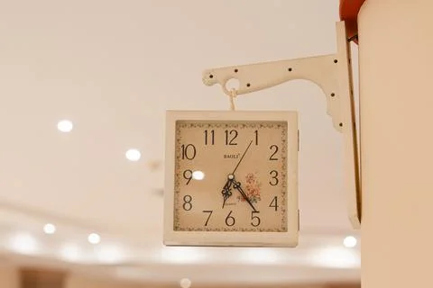 Vintage square clock hanging on a wall displaying time Stock Photos