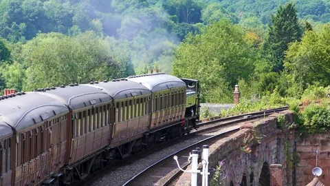Vintage steam engine pulling carriages over railway bridge Stock Footage 80288201