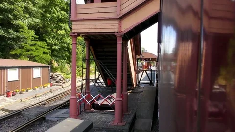 Vintage steam train passing under countryside station bridge Stock Footage 80314190