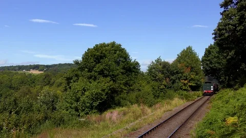 Vintage steam train producing smoke travelling through countryside Stock Footage 80332426
