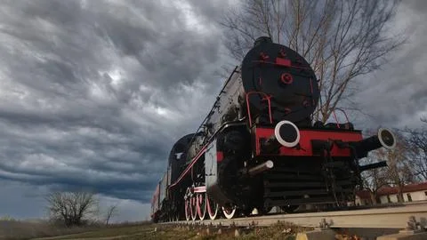 A vintage steam train under dramatic stormy skies, evoking nostalgia and powe Stock Photos