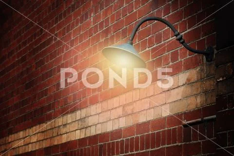 Vintage street light shining on a red brick wall Stock Photos