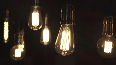 Vintage style light bulbs swinging on the wire in the house. Decorative light Stock Footage 129136174