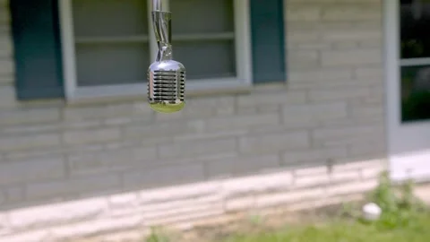 Vintage style microphone hanging bouncing outdoors, House facade as Stock Footage 205865564