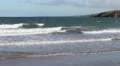 vintage style pan of wave rolling into the beach, blue sky and mountains HD Footage