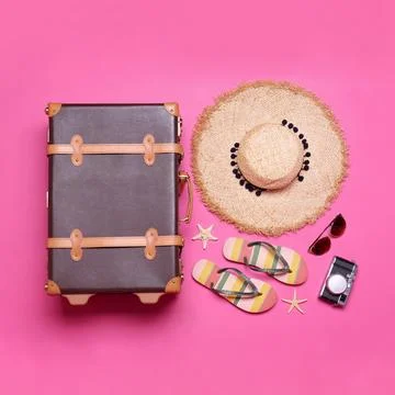 Vintage suitcase and beach objects on pink background, flat lay Stock Photos