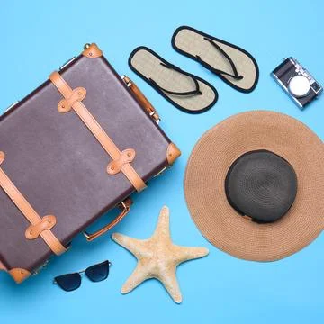 Vintage suitcase and beach objects on blue background, flat lay Fotos de archivo