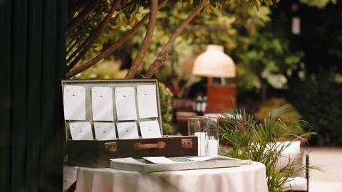 Vintage Suitcase With Wedding Seating Cards on Garden Table Stock Footage 346498286