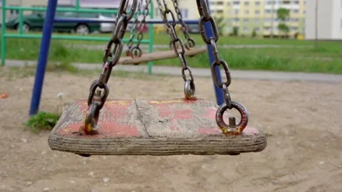 Vintage swings with rusty chains waved by wind on playground Stock Footage 135296901