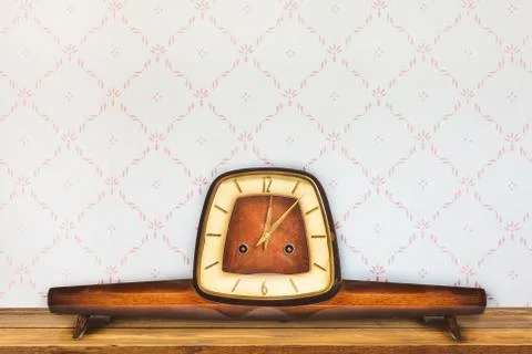 Vintage table clock in front of retro wallpaper Stock Photos