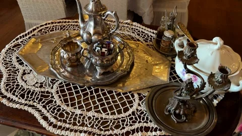 Vintage tea set and silverware displayed on lace covered wooden table Stock Footage 323343581