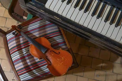 Vintage violin without strings resting on a retro striped chair next to an .. Stockfoto's