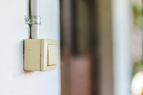 Vintage wall mounted light switch with exposed electrical conduit in rustic.. Stock Photos