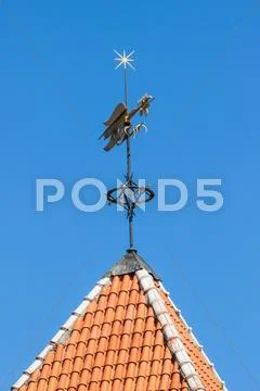 Vintage weather vane cock bird on the red roof a Stock Photos