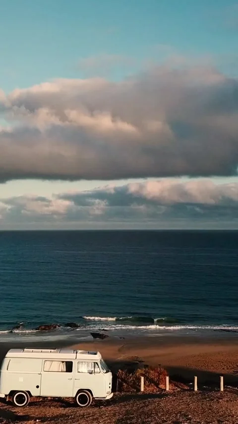 Vintage white camper van parked on a scenic coastal cliff with beautiful ocean Stock Footage 344820377